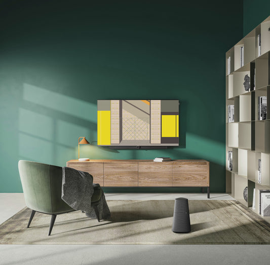 Animated mockup of the Ordre Minimal wallpaper collection displayed on a TV in a sophisticated living room with dark green walls. On the screen, a slideshow of the "Place d'Armes: The Brutalist Gateway" illustration cycles through its twelve different colour themes, including the authentic Classic '66, the warm Notre Nocturne, and the cool, aquatic Le Fleuve.